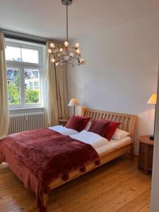 a bedroom with a bed with red pillows and a chandelier at seeglueck SEELIEBE Stadtlage in Konstanz