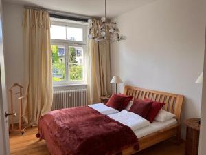 Un dormitorio con una cama con almohadas rojas y una ventana en seeglueck SEELIEBE Stadtlage en Konstanz