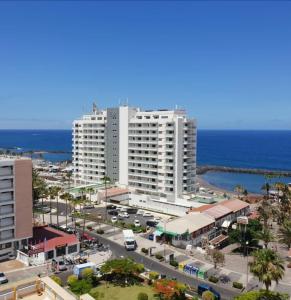 un gran edificio blanco frente al océano en Magnific flat Copacabana with ocean view, en Playa de las Américas