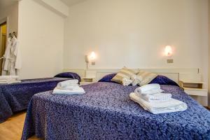 a bedroom with two beds with towels on them at Hotel Tiziana in Rimini