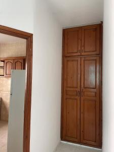 Cette chambre dispose d'une porte en bois et d'un réfrigérateur. dans l'établissement Appartement spacieux, Résidence Les 5 étoiles, Bizerte, à Zarzouna