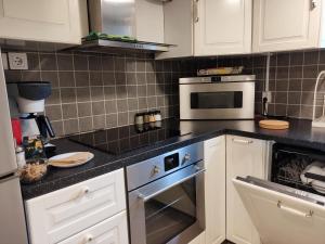 uma cozinha com armários brancos e um forno com placa de fogão em 90 m2 charmig källarlägenhet nära natur och stad em Mölndal