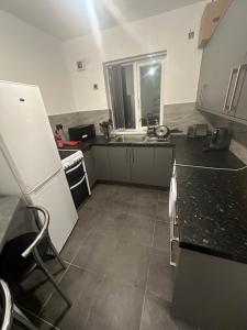 Sutton Coldfield Apartment في برمنغهام: مطبخ مع ثلاجة بيضاء ومغسلة
