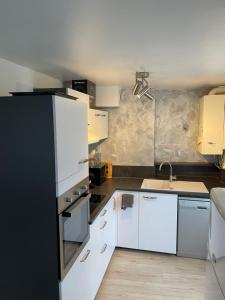 a kitchen with white cabinets and a black refrigerator at Charmant appartement Orléans ! in Orléans