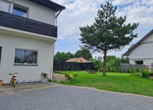 una casa blanca con un árbol en el patio en Pokoje Gościnne u Marysi, en Nowy Sącz