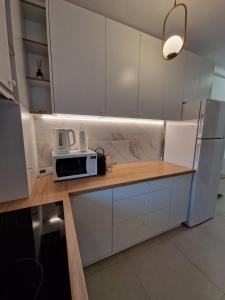 una cocina con armarios blancos y microondas en una encimera en Cora Apartment, en Baia Mare