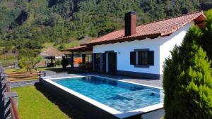a villa with a swimming pool in front of a house at Quinta do Conde by LovelyStay in Fajã do Penedo