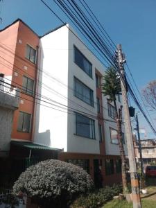 een wit gebouw met een palmboom ervoor bij Luminoso y confortable apartamento a 6 min aeropuerto in Bogota
