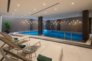 a pool with chairs and tables in a building at Marlo Hotel in Jeddah