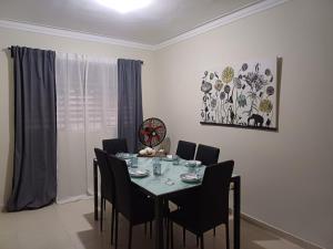 a dining room with a table with chairs and a clock at Bello Apartamento, 2 habitaciones 2 baños Santo Domingo Carmen Renata III in Santo Domingo