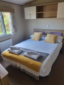 1 dormitorio con 1 cama grande y toallas. en Newquay Bay Porth Caravan - 6 berth en Newquay