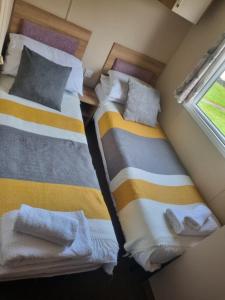 two beds in a small room with a window at Newquay Bay Porth Caravan - 6 berth in Newquay