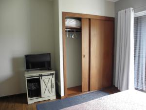 1 dormitorio con armario, TV y puerta en Alice´s House en Horta