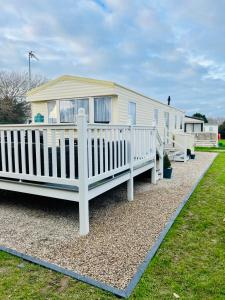 a mobile home with a white railing and a porch at Shell Beach Holiday Home Mersea Coopers Beach in East Mersea