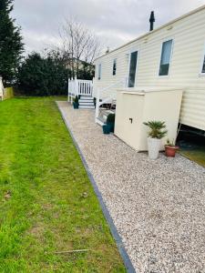 a house with a gravel driveway next to a yard at Shell Beach Holiday Home Mersea Coopers Beach in East Mersea