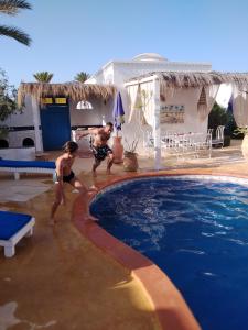 dos personas jugando en la piscina en un complejo en Dar Aladin en Arkou