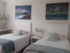 a bedroom with two beds and two pictures on the wall at Marlin Cottage in Chintsa