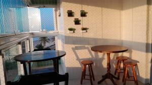 dwa stoły i stołki w pokoju z oknem w obiekcie Belíssimo apartamento frente mar w mieście Mongaguá