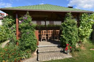 a gazebo with chairs and flowers in a garden at Vasarnamis Zarasuose - Vyšnia in Zarasai