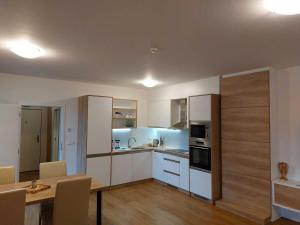 a kitchen with white cabinets and a table with chairs at Apartmány NETA Velké Karlovice, Polanský Dvůr in Velké Karlovice