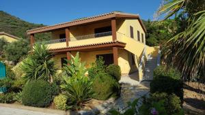 een geel huis met een balkon erboven bij Appartamento in splendido e riservato villaggio, marina di Tertenia in Tertenìa