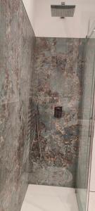 a shower in a bathroom with a stone wall at Casa Mariettina in Sottomarina
