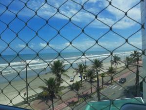 uma vista para uma praia com palmeiras e para o oceano em Belíssimo apartamento frente mar em Mongaguá