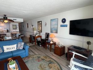 a living room with a blue couch and a flat screen tv at 405 Waters Edge in Myrtle Beach