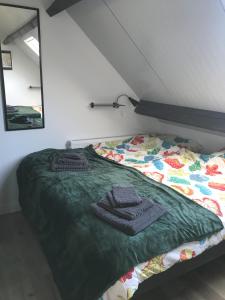 a bed with a green comforter and a mirror at Boerderij de Zalm in Schalkwijk