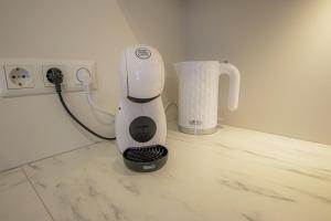 a white blender sitting on a counter next to a cup at Fortune Apartments - River view, Contactless in Tartu