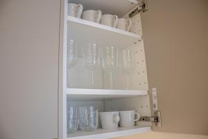 a cabinet filled with glasses and mugs at Fortune Apartments - River view, Contactless in Tartu