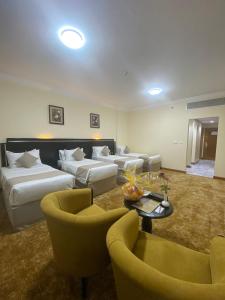 a hotel room with two beds and a table and chairs at Bab Al Multazam Concorde Hotel in Makkah