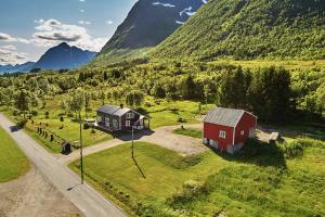 Cozy home in Godfjord في سورتلاند: اطلالة جوية على بيت وحظيرة في الجبال