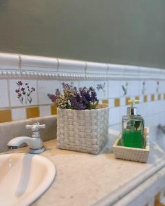 um lavatório de casa de banho com uma garrafa de sabão e flores em Hostel 040 em Itaipava