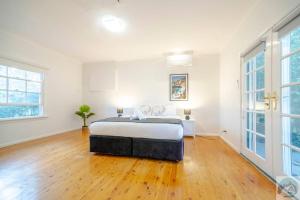 1 dormitorio blanco con 1 cama y suelo de madera en Aircabin - Beecroft - Sydney - 3 Bed Holiday House, en Beecroft