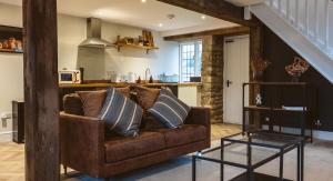 a living room with a brown couch and a kitchen at Gardener's Cottage in Chepstow