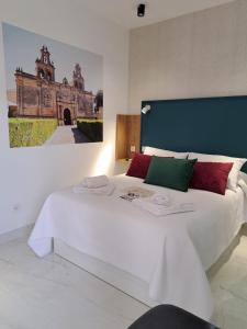 1 dormitorio con 1 cama blanca grande con una foto en la pared en VIVAL RASTRO DELUXE, en Úbeda 30 fotos más