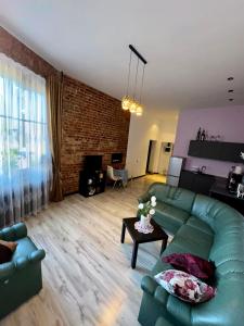 ein Wohnzimmer mit einem grünen Sofa und einer Ziegelwand in der Unterkunft Saules Apartament in Daugavpils