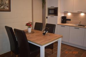 a kitchen with a wooden table and black chairs at Hengelhoef DEN 5 volledig gelijkvloers Vakantiehuisje voor 4 p 2 terrassen en verwarmd openlucht zwembad in Houthalen-Helchteren