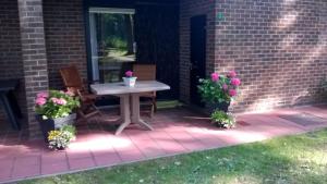 eine Terrasse mit einem Tisch, 2 Stühlen und Blumen in der Unterkunft Hengelhoef DEN 5 volledig gelijkvloers Vakantiehuisje voor 4 p 2 terrassen en verwarmd openlucht zwembad in Aan de Wolfsberg