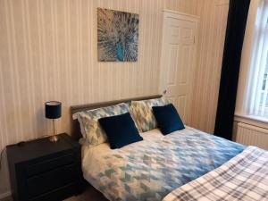 a bedroom with a bed with blue pillows on it at Springfield Apartment - Train to Glasgow or Edinburgh - Private Parking & Wifi in Airdrie +24 photos