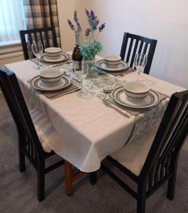 einen Esstisch mit einem weißen Tischtuch drauf in der Unterkunft Springfield Apartment - Train to Glasgow or Edinburgh - Private Parking & Wifi in Airdrie