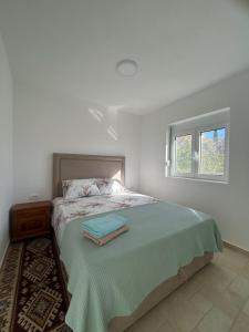 a white bedroom with a bed with a window at Villa Marina in Dobra Voda