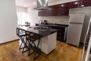 a kitchen with a black counter top and a white refrigerator at El Suburbio - Serapio Rendon in Morelia