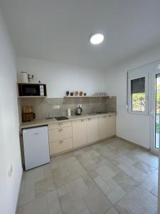 a kitchen with white cabinets and a white refrigerator at Villa Marina in Dobra Voda