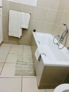 a bathroom with a white bath tub and a rug at 82 St Andrews Jackal Creek Golf Estate with Backup power & Golf course views in Roodepoort