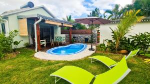 a backyard with a pool and chairs and an umbrella at Bungalow Citronnelle in Saint-Pierre