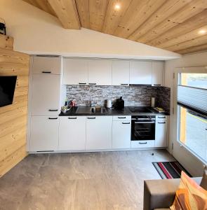 eine Küche mit weißen Schränken und einer Ziegelwand in der Unterkunft Chalet Lilo New Studio in Beatenberg