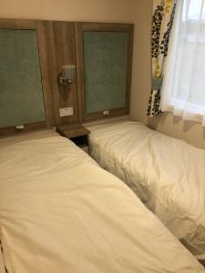 two beds in a room with two windows at Lovely Caravan in Turnberry