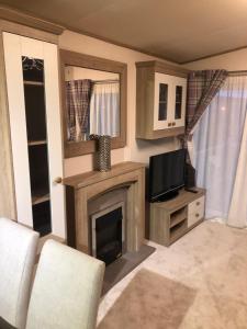 a living room with a fireplace and a tv at Lovely Caravan in Turnberry